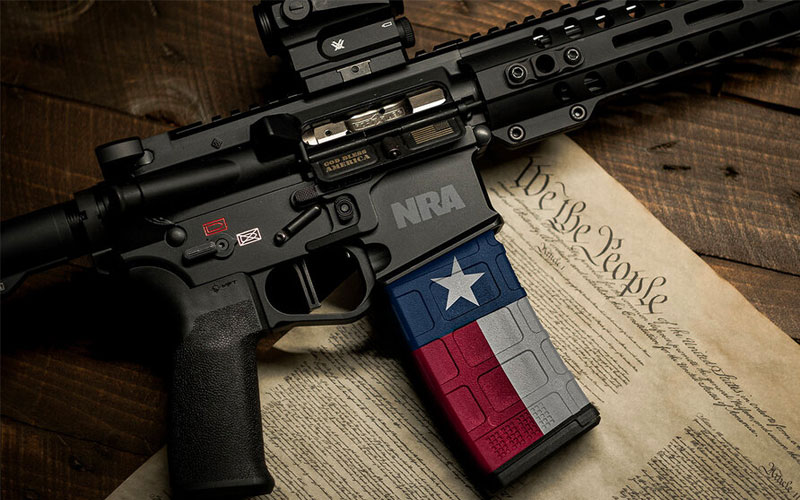 AR15 with NRA logo and Texas flag magazine atop Constitution